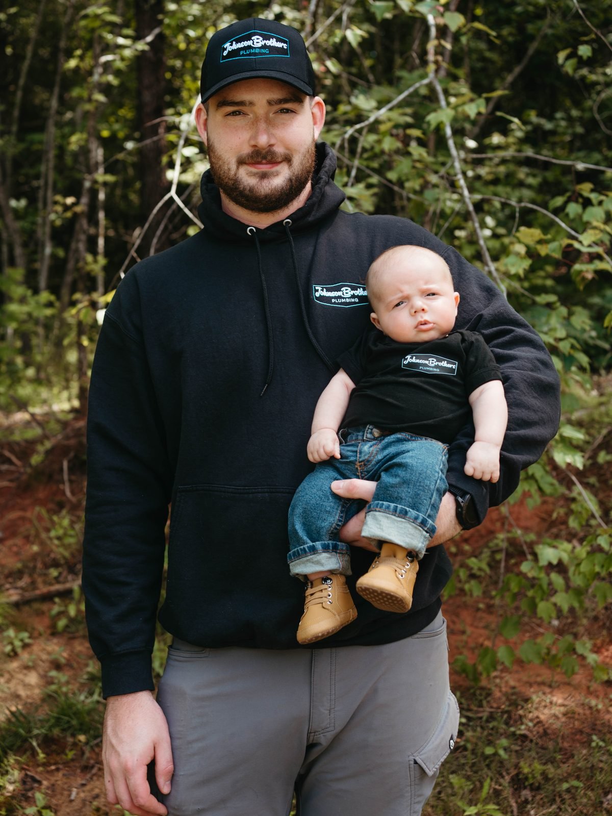 Johnson Brothers Plumbing founder Jacob Johnson holding his son Jack, both in Johnson Brothers shirts